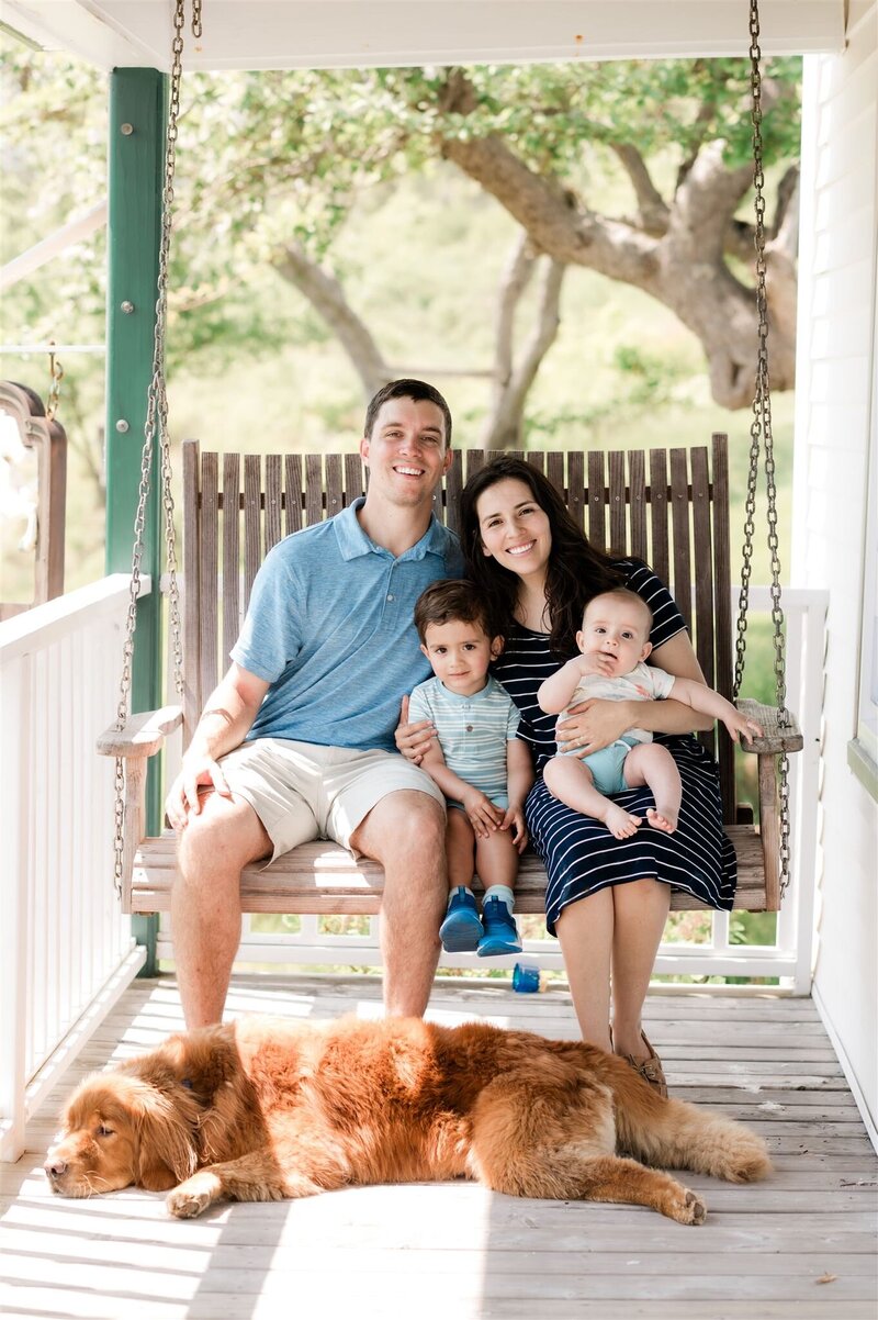 A family sitting on a porch swing during their cape breton family photography session with Candace of CDM Photography