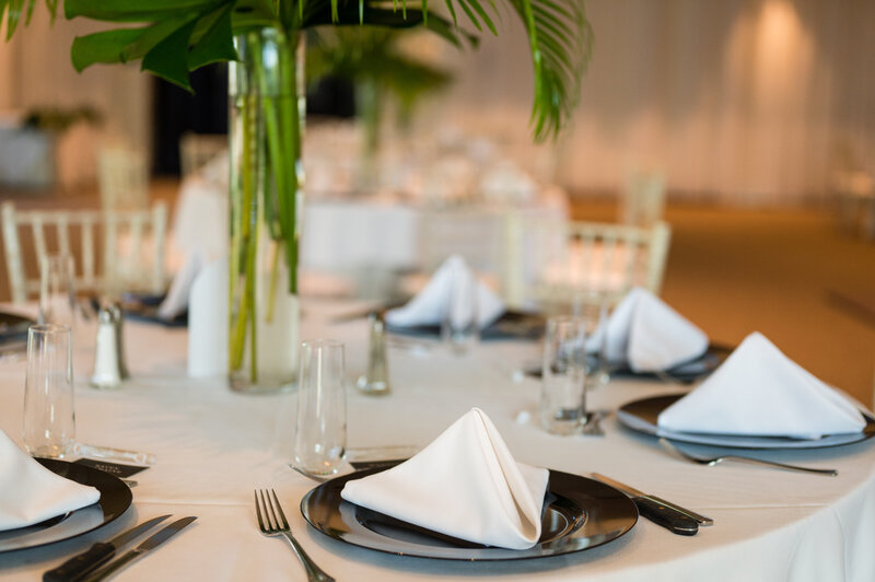 Elegant table settings with green foliage centerpieces by Jennifer’s Floral Designs.