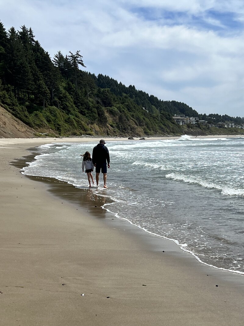 Father and child walking a quiet beach — exploring togetherness and emotional roots in expat family travel