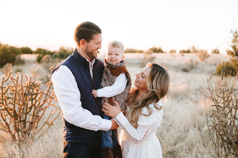 mom, dad and son smiling at each other 