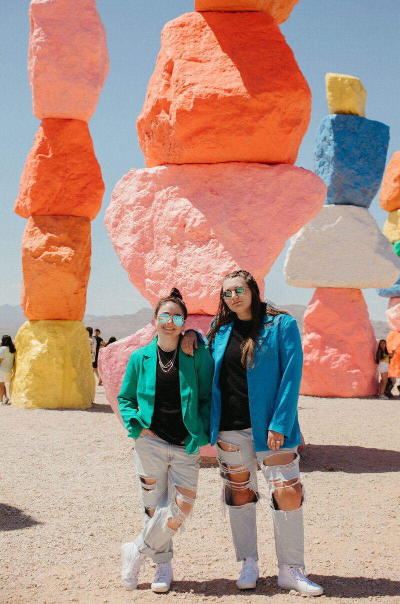 Two girls pose in front of colored rocks.