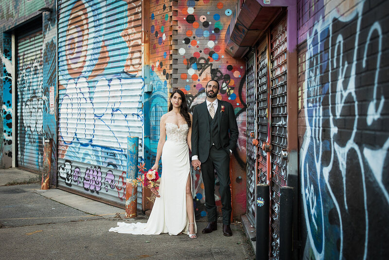 Bride and groom holding hands with graffiti Brooklyn backdrop