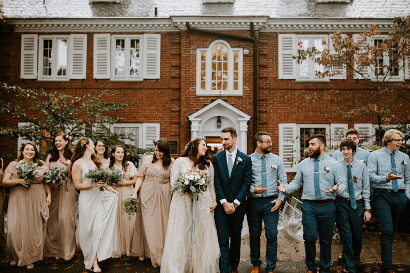 bride and groom looking at each other and standing in front of their wedding party