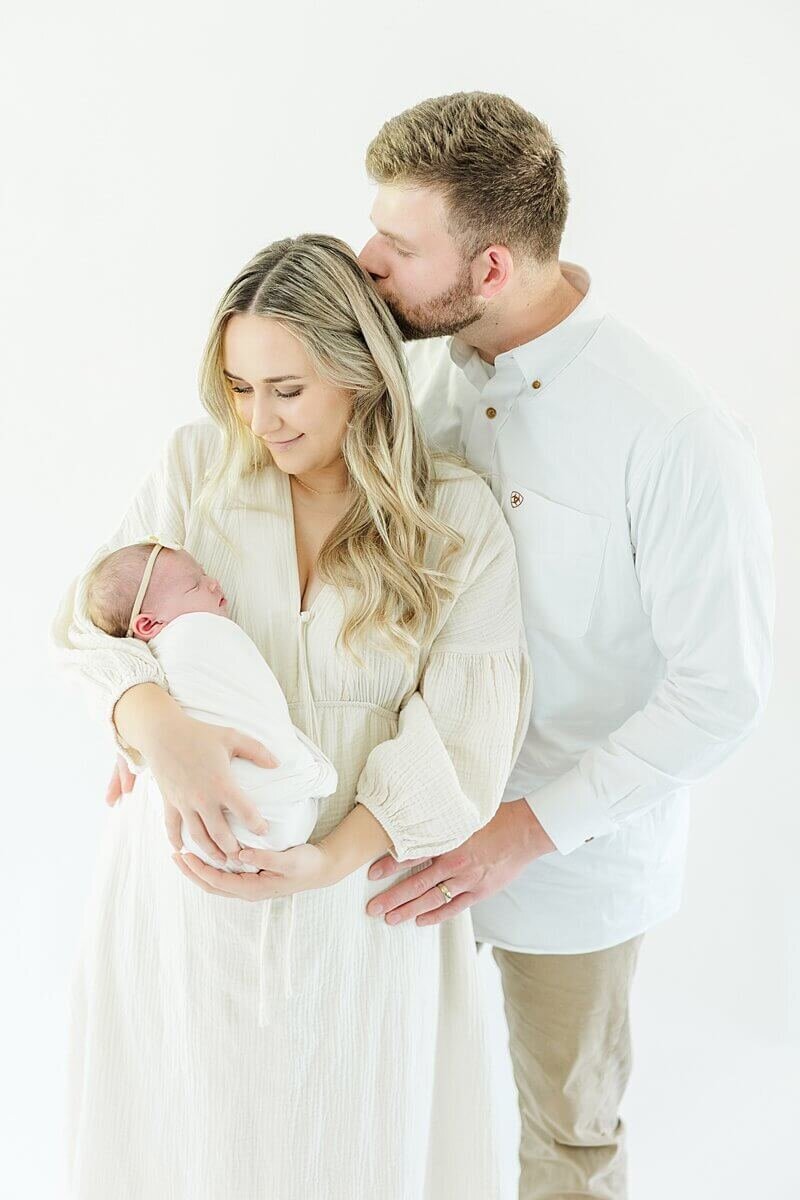 Studio Newborn photo of mom and dad holding newborn baby girl near Greenville, NC