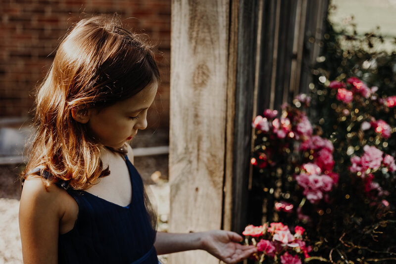 young girl looking at pink flowers