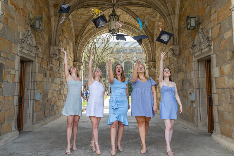 Five young women are tossing their graduation caps in the air at the University of Michigan Law Quad