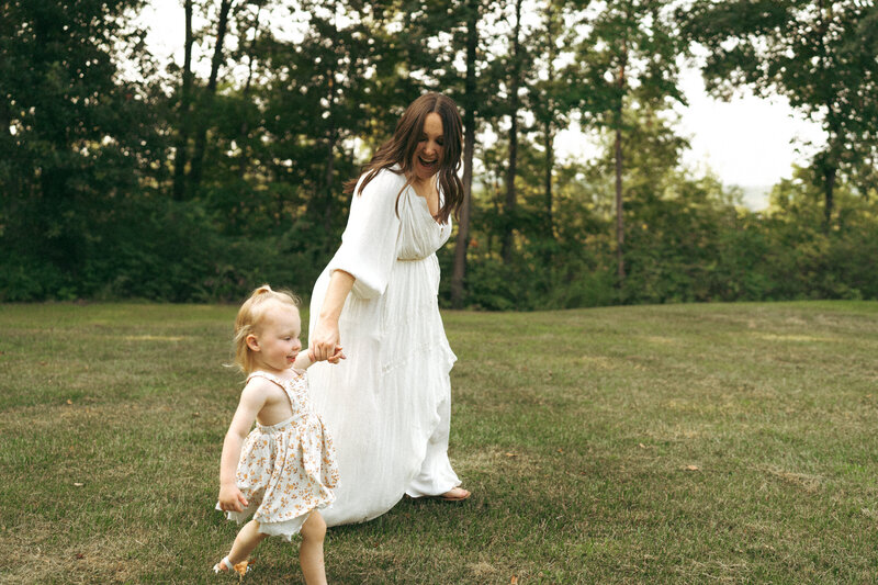 pregnant mom holding daughter's hands 