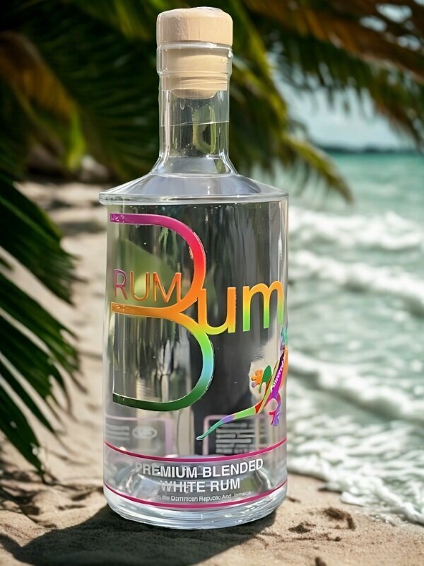 Close-up of a transparent rum bottle labeled “Rum Bum” with a rainbow-colored logo and a small gecko, positioned against a tropical beach backdrop.