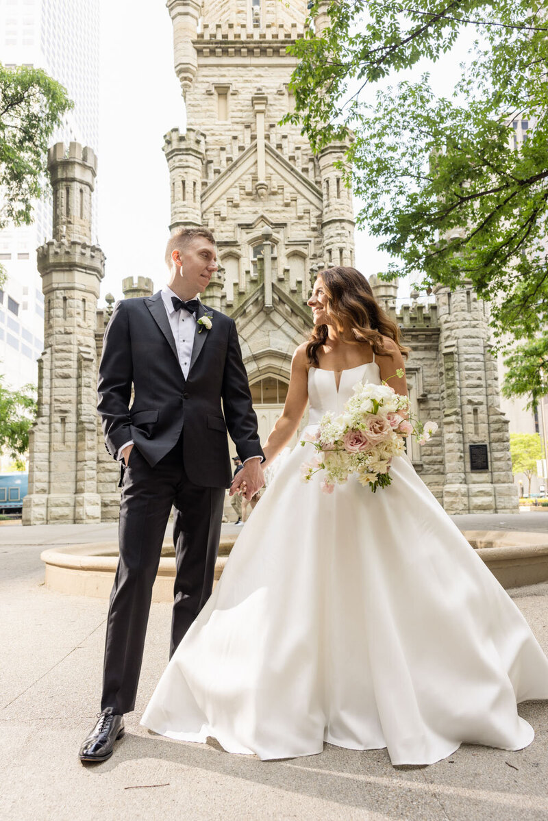 A bride and groom are holding hands in front of a church.