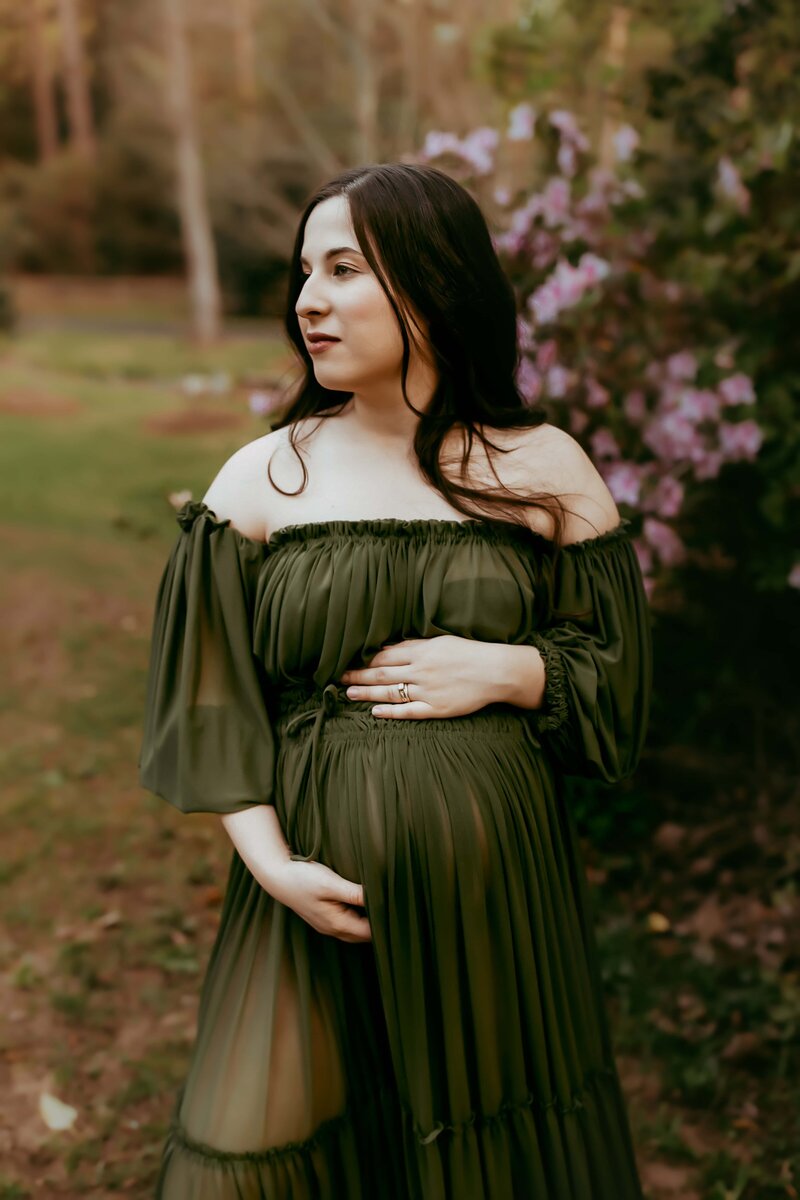 A pregnant woman in an olive green dress posing for a maternity photo session with Macon GA photographer.