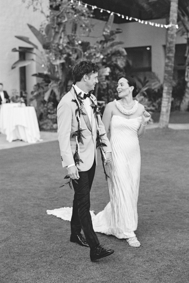 Wedding and Elopement Photography, black and white image of couple looking at each other smiling walking across the grass