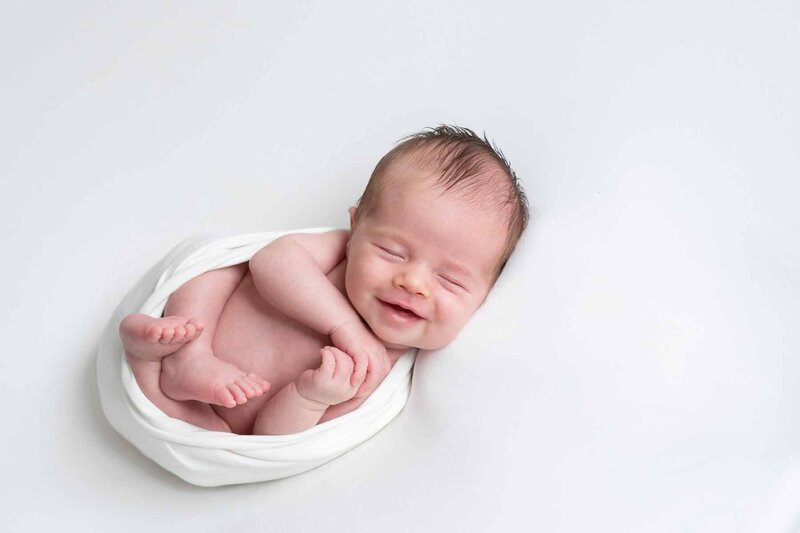Lachende baby op witte achtergrond. Newborn shoot thuis. Irene Maris Fotografie
