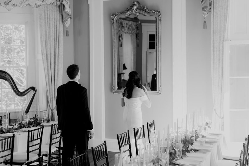 Wedding couple is looking into the mirror at reception place before guests enter.