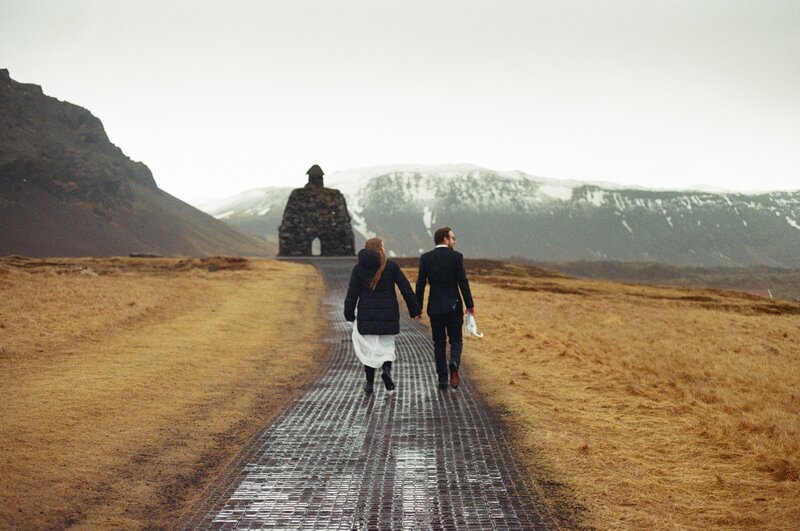 Bride and groom walking to their epic outdoor Iceland elopement ceremony on a rainy day
