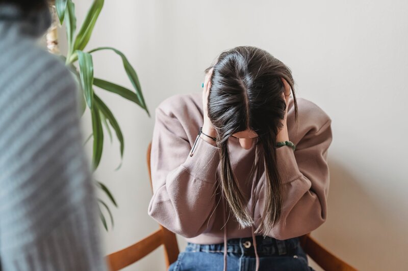 Une femme assise qui  tient sa tête entre ses mains