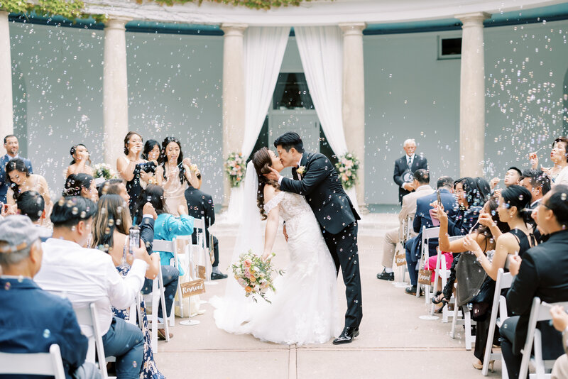 couple kissing in the aisle with surrounded by bubbles