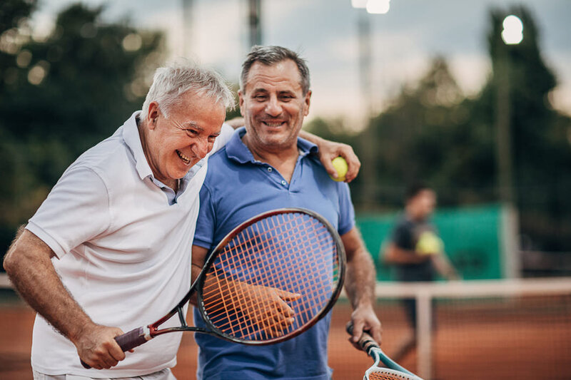 man putting his arm around another after playing a game of tennis