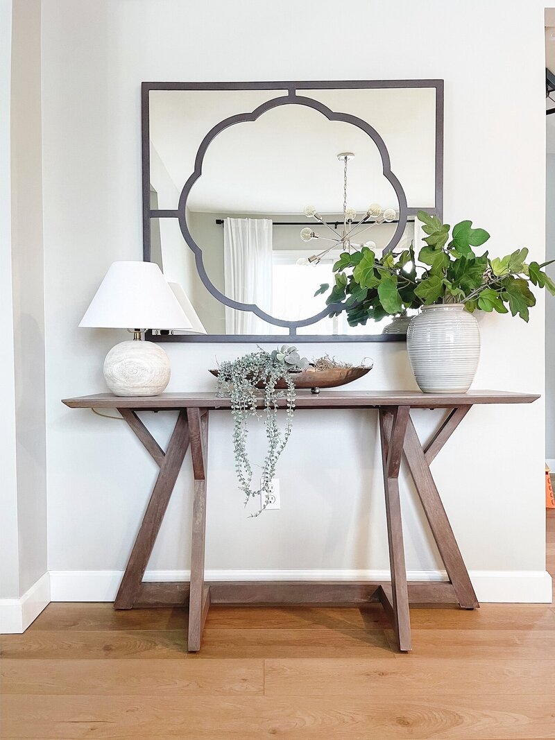 Dark wooden table with a large plant and mirror.