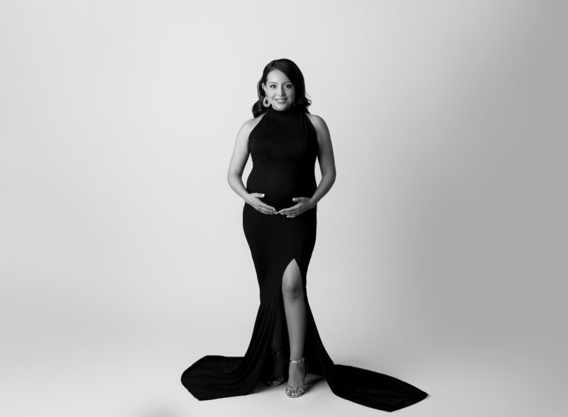 pregnant woman black dress with leg slit white background