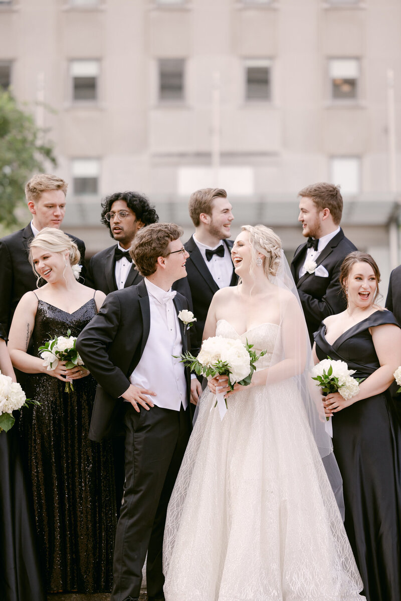 Candid photo of a bridal party laughing with bride and groom