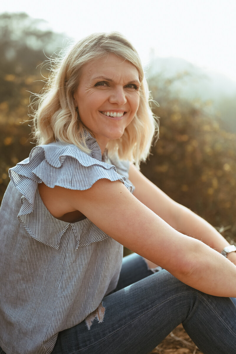 Emily Collins smiling in natural light during a calm morning outdoors.