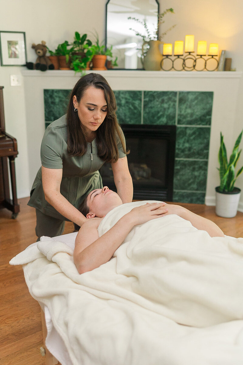 Candice massaging the neck of a client as they lay on the massage table