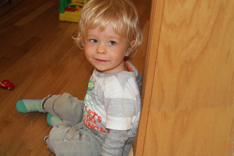 Young blonde boy smiling sitting on wooden floor