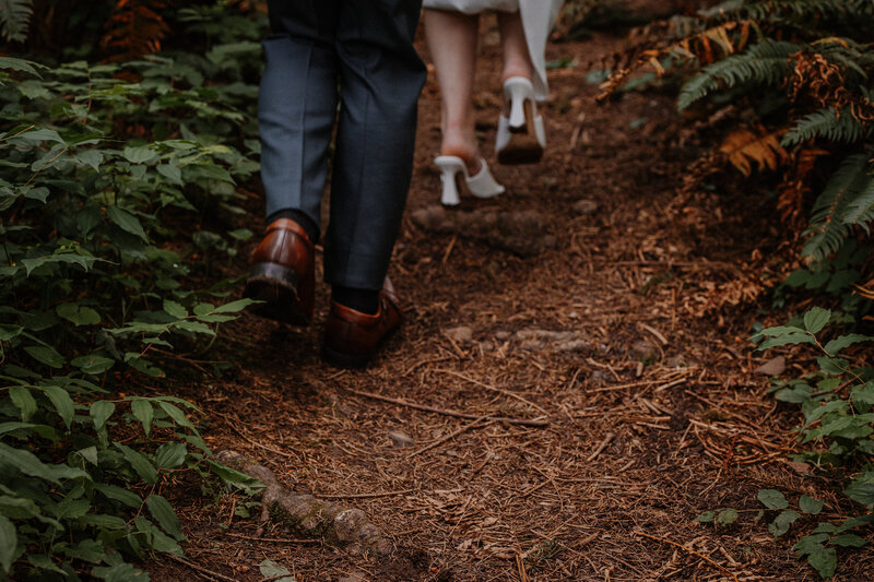 Bride and groom hiking up trail with wood chips