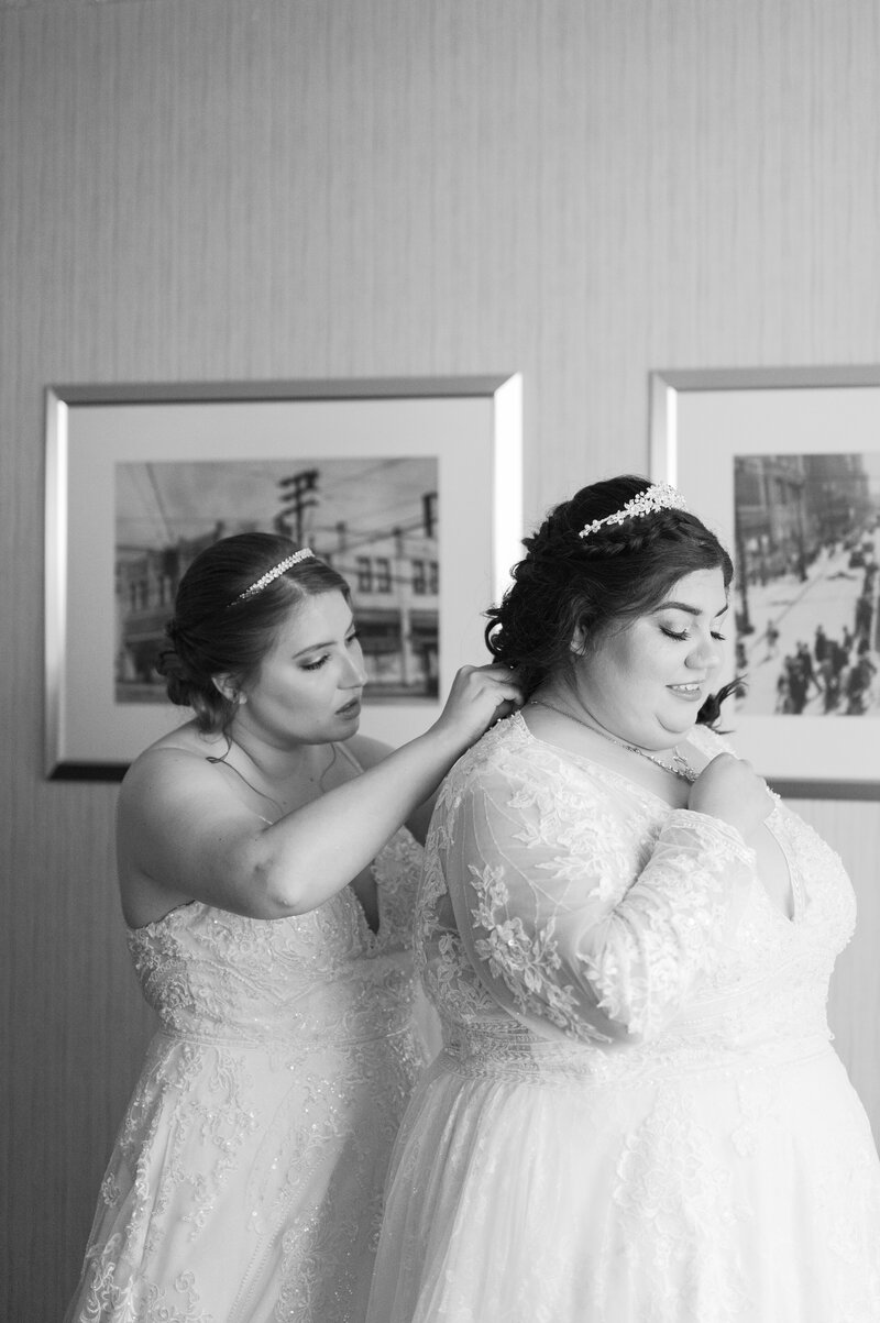 bride helps fastensoon to be wife with lace wedding gown before the ceremony, captured by wedding photographer Cleveland Ohio

