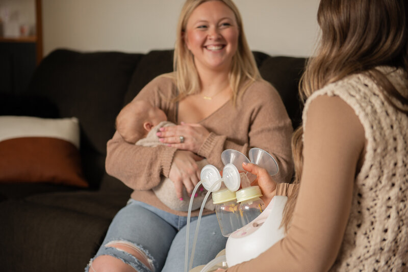 woman holding infant while being shown a pump