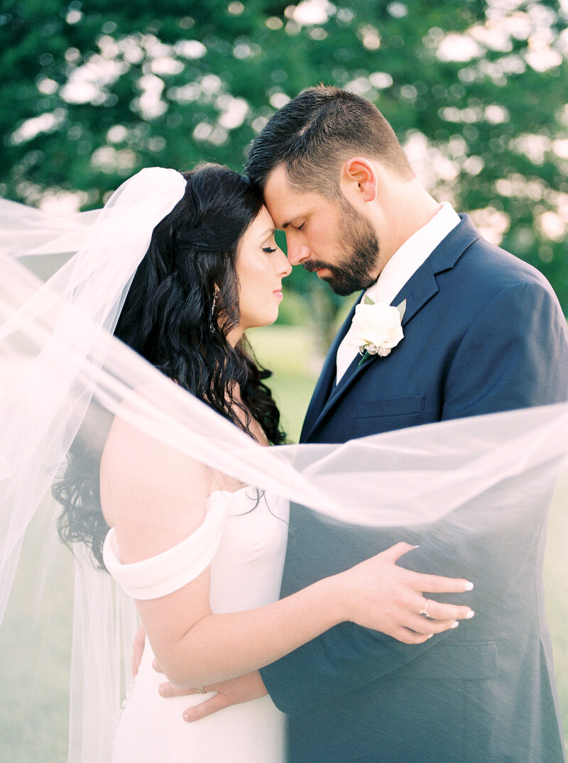 bride and groom closing eyes facing each other