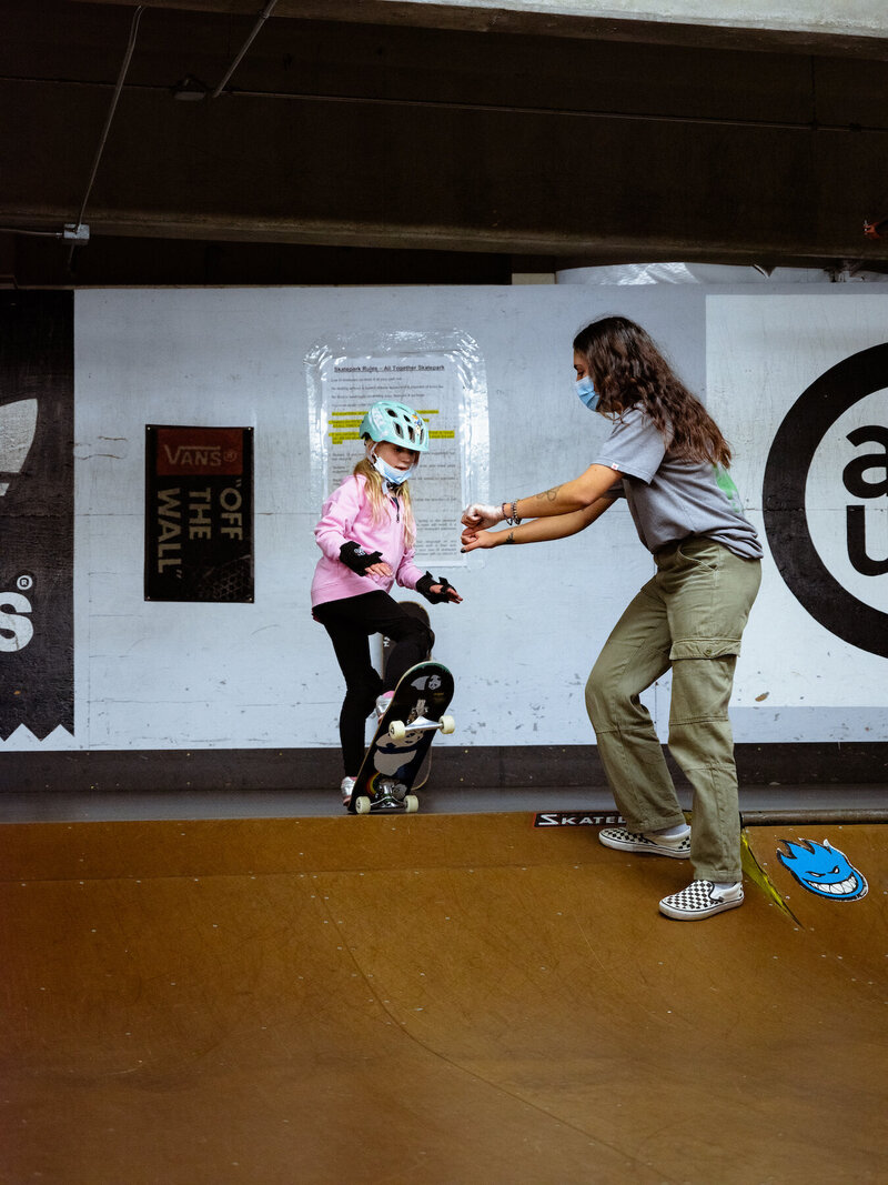 Seattle skateboarding teacher helping young girl skate