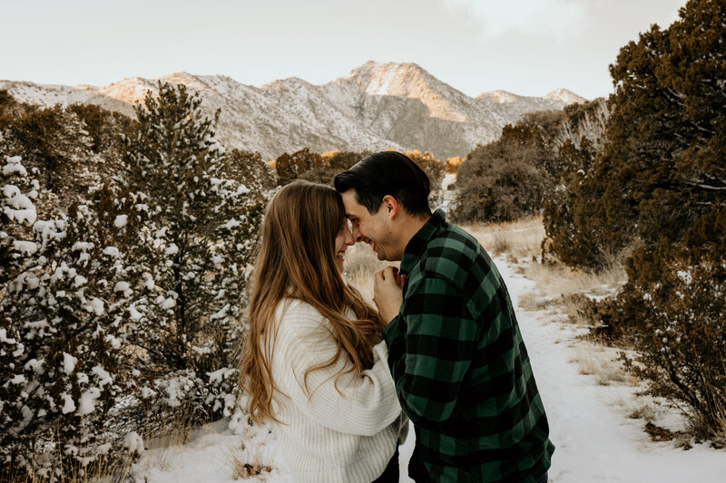 engaged couple holding hands in the snowy Albuquerque mountains