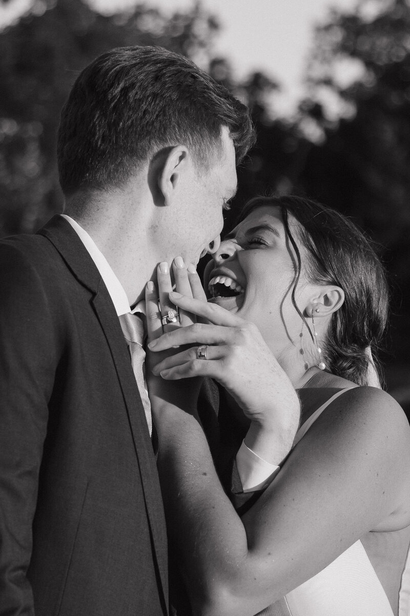 bride and groom embracing while smiling at each other