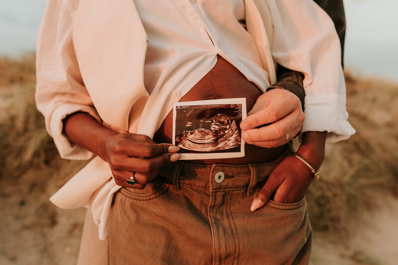 couple holding ultrasound scan at the beach