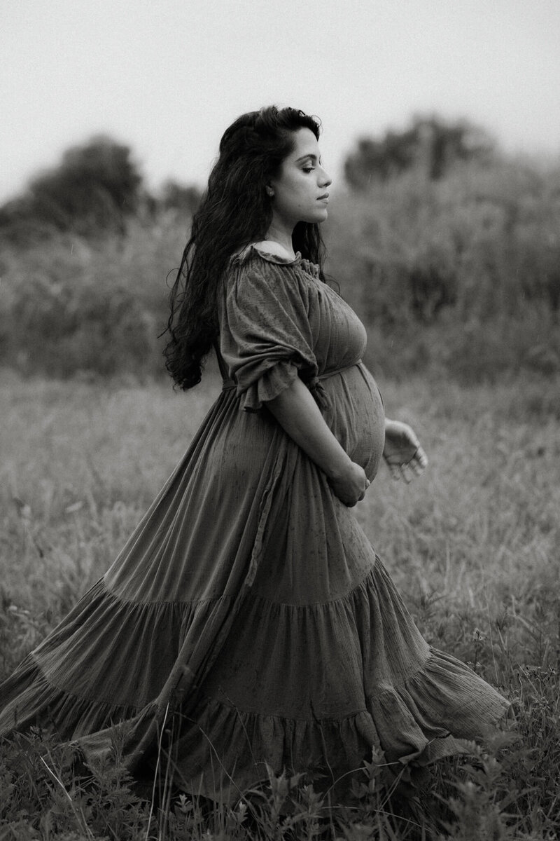 black and white photo of maternity walking in the grass