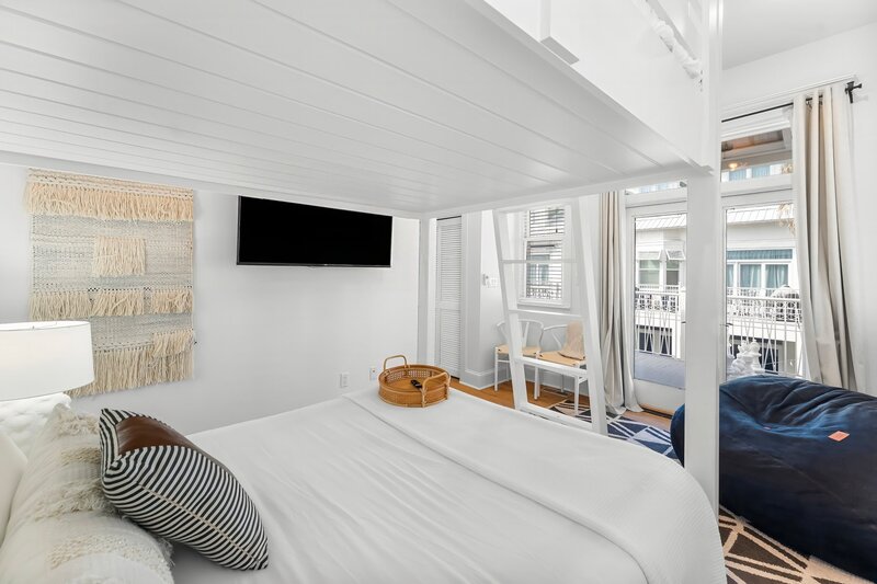 Cozy bunk bed room with TV and private balcony access in Panama City Beach rental.