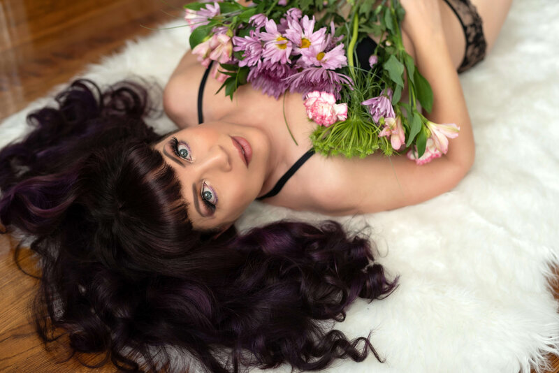 Boudoir portrait of woman with blush wings in a studio setting, tattoos on arm