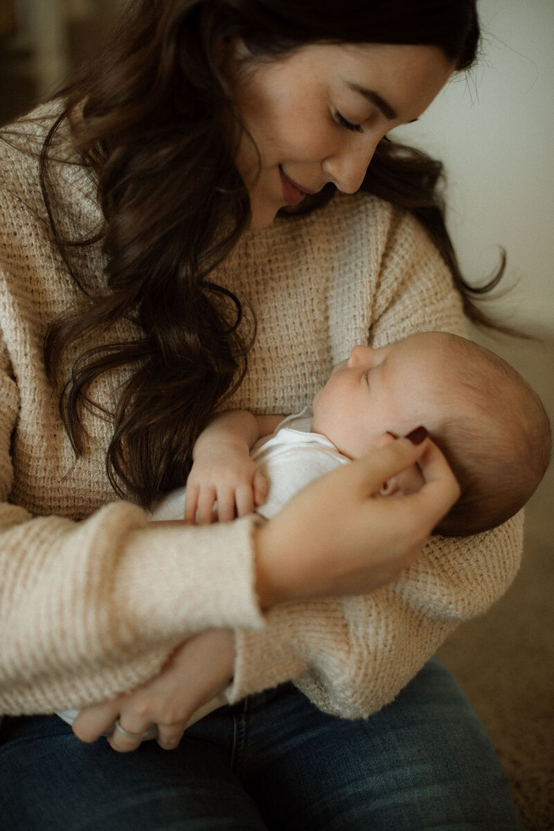 Mother gently holding her newborn son during a serene in-home newborn session in Canyon Lake, California.