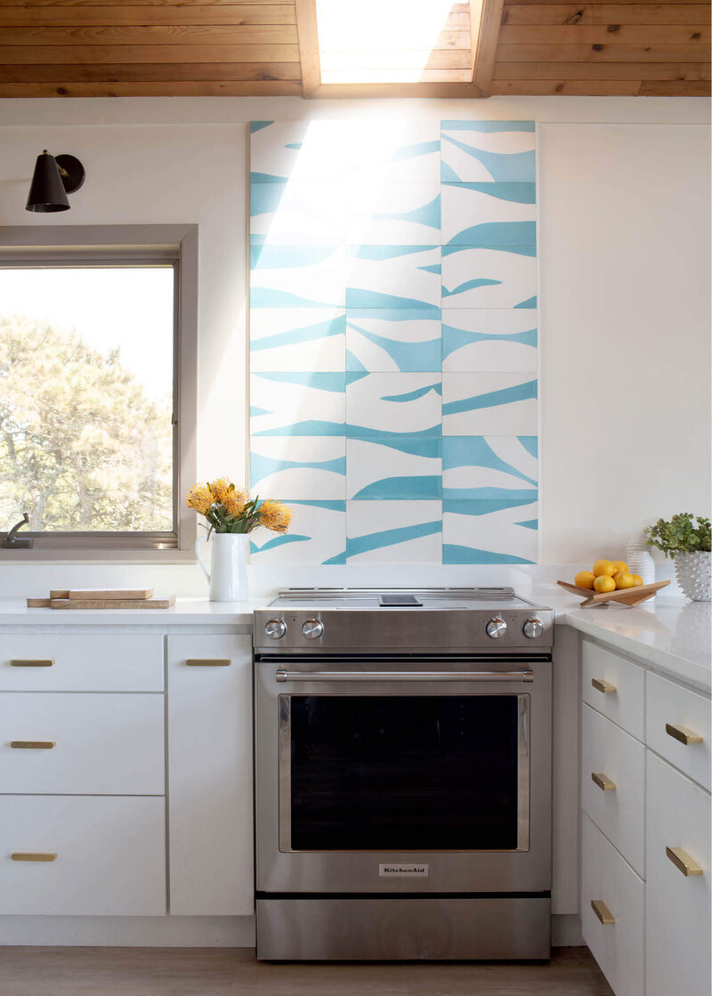 Martha’s Vineyard interior designer designs a kitchen with white cabinets and custom concrete tiles from Popham Tile and Ann Sacks above the range.