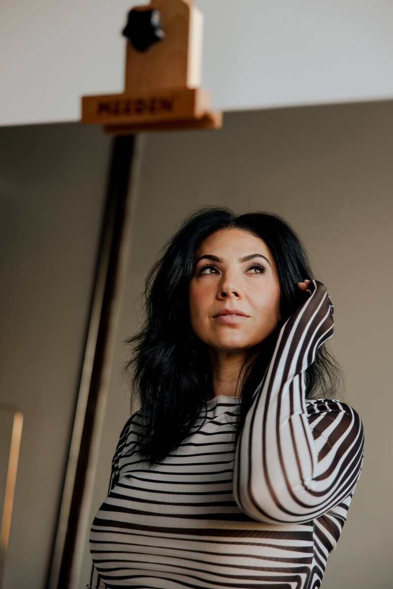 Angelica Ray, personal growth and spiritual guide, looking thoughtful in a striped top.