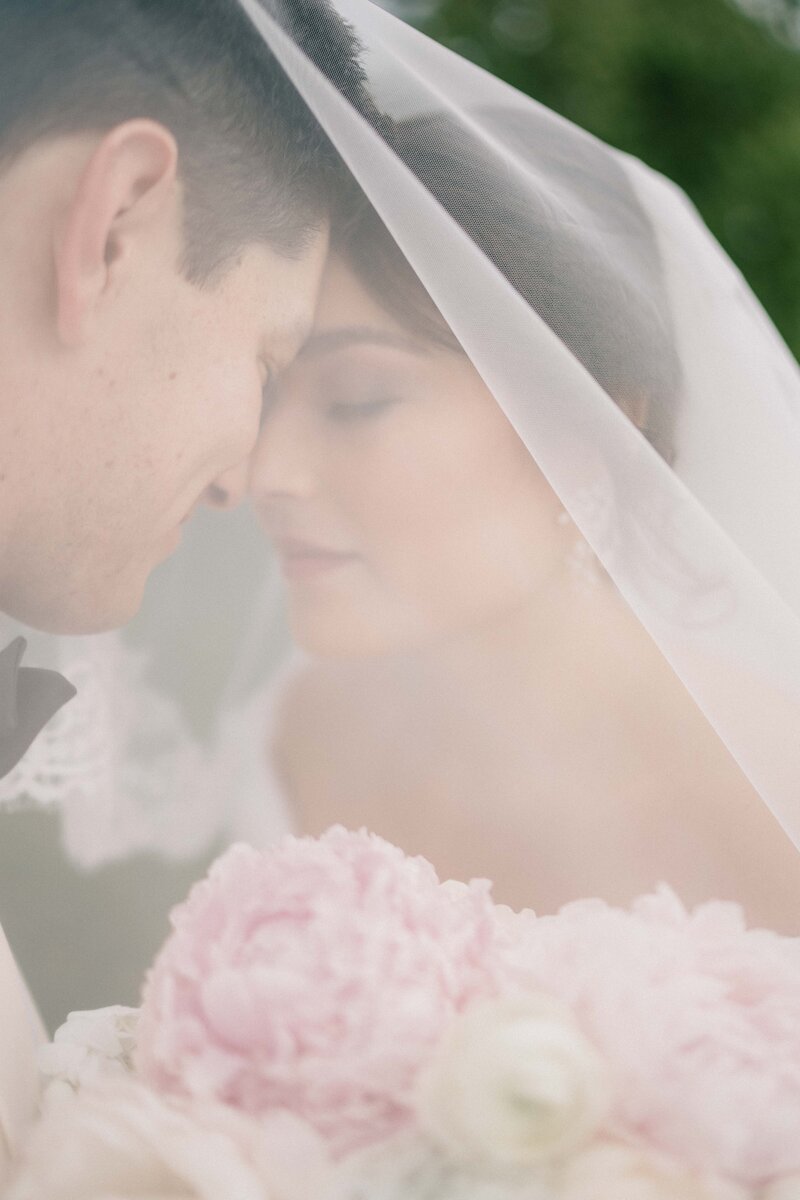 bride and groom close their eyes under the veil portrait