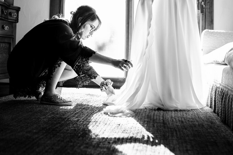 bride gets in dress near window while her sister helps her