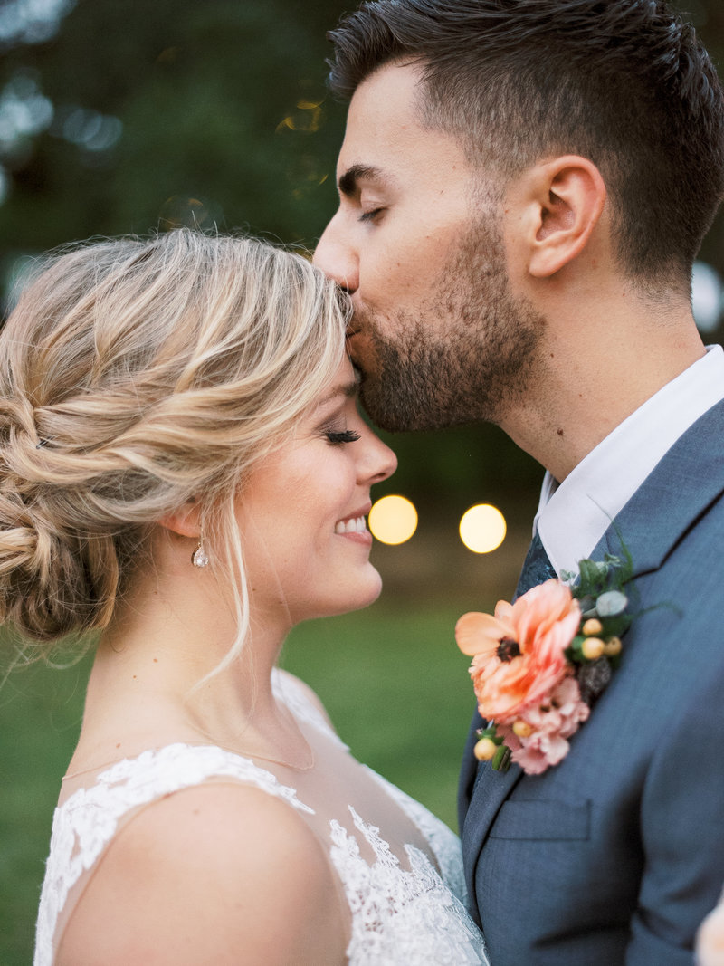 Groom kisses bride on forehead