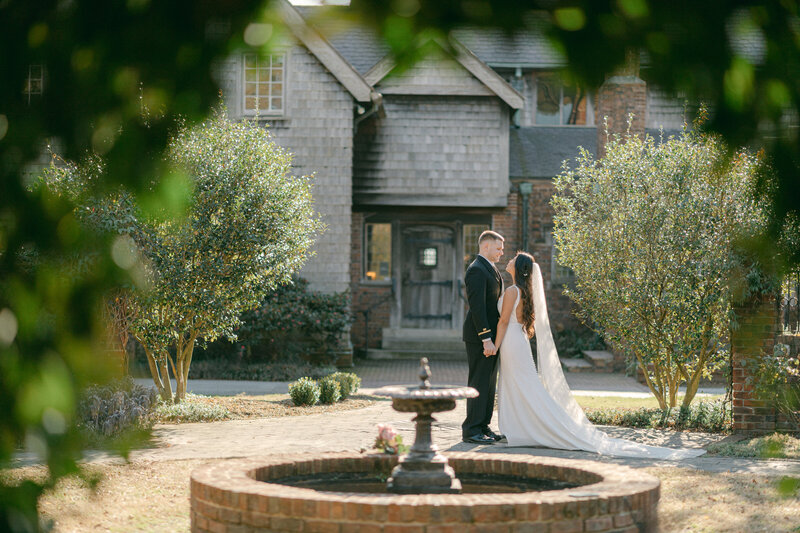Virginia Wedding photography of a Bride and groom  standing behind the fountain holding hands and looking at each other