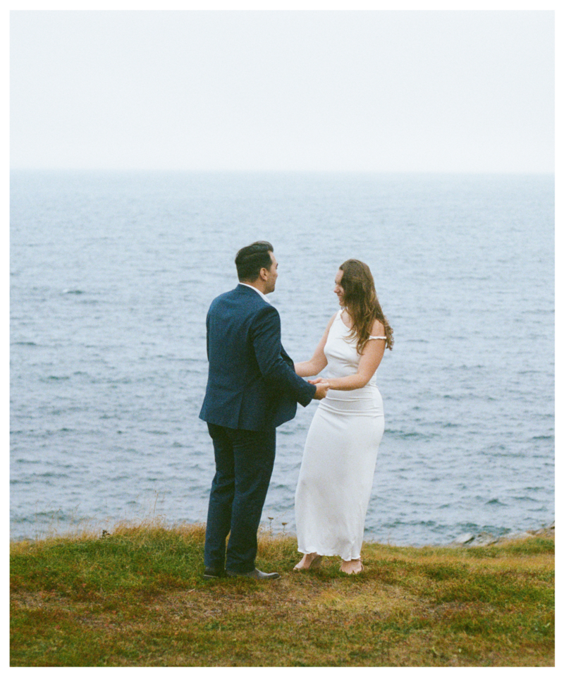 bride and groom stand on a foggy sea cliff