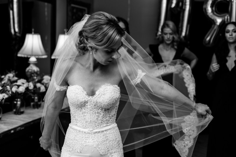 Black and white wedding photo of bride getting dressed