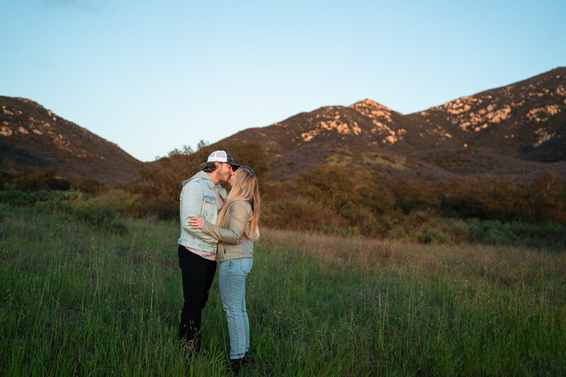 Couple holding hands and kissing  on the beach in San Diego, California