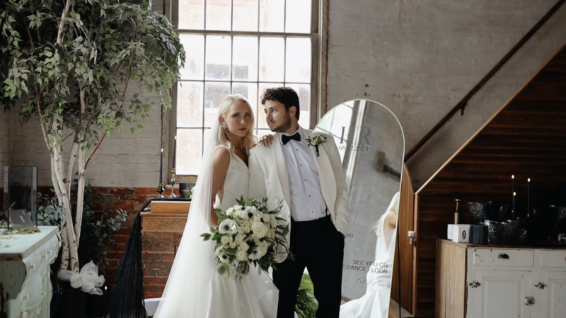 bride and groom standing in their venue looking at the camera with a serious face