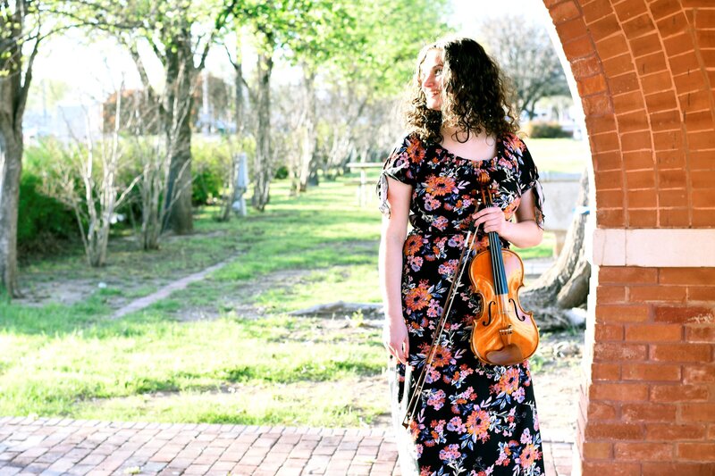 Violin teacher and Franklin Method Educator Dr. Erika Burns holding a violin in a park.